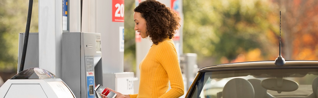 A woman at the gas pump using her phone to pay