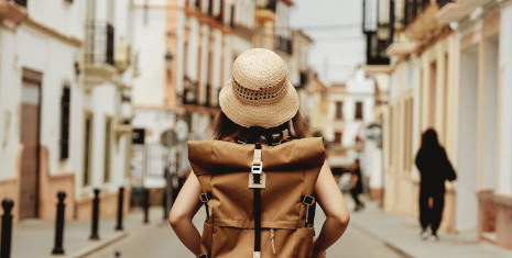 Woman walking down the street with a hat and backpack on
