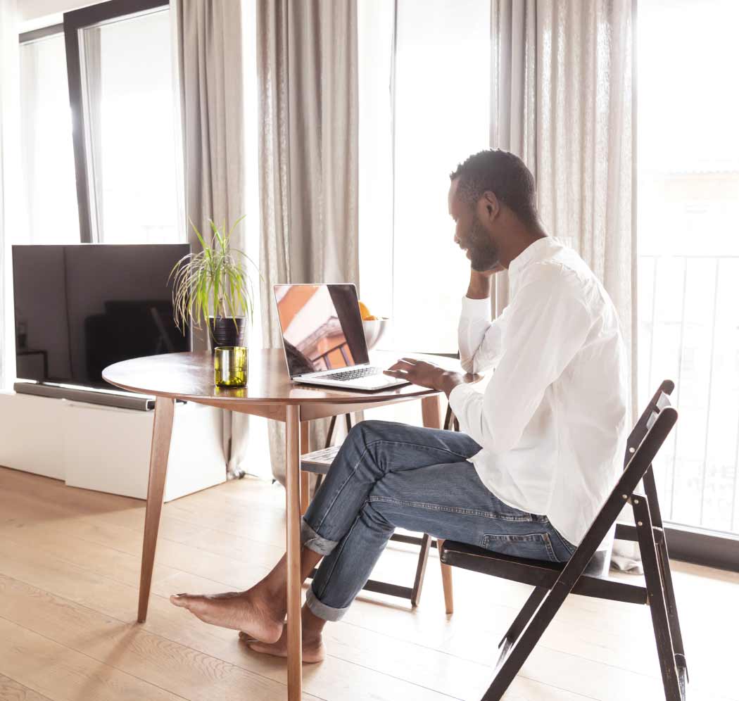 man sitting at desk looking at laptop