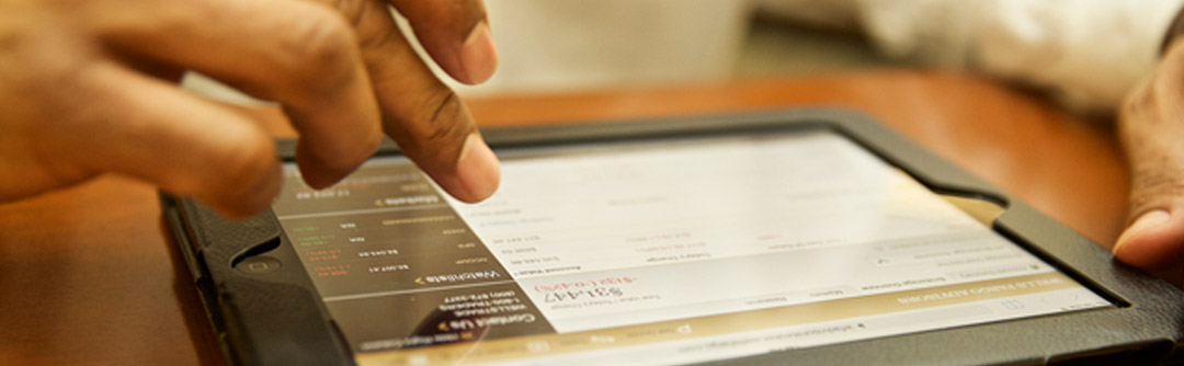 Closeup view of user's hands and a tablet; user is viewing their investment account on the tablet