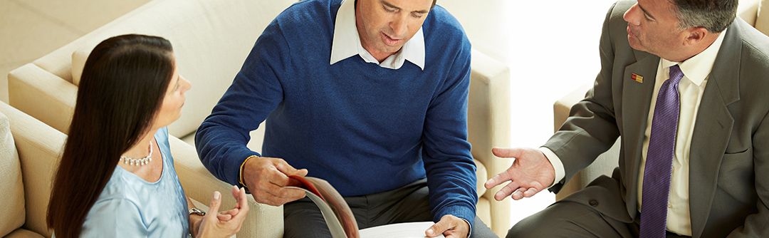 Man and woman speaking with financial advisor and looking over a booklet