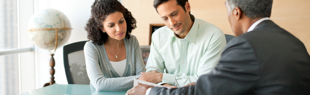 Man and woman speaking with financial advisor and looking over a document