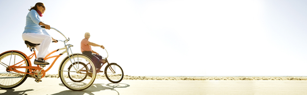 A man and a woman riding bikes down a beachside sidewalk