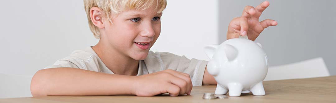 Child putting money into a piggy bank