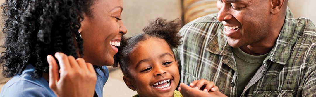 Mom, dad, and toddler-aged daughter laughing together