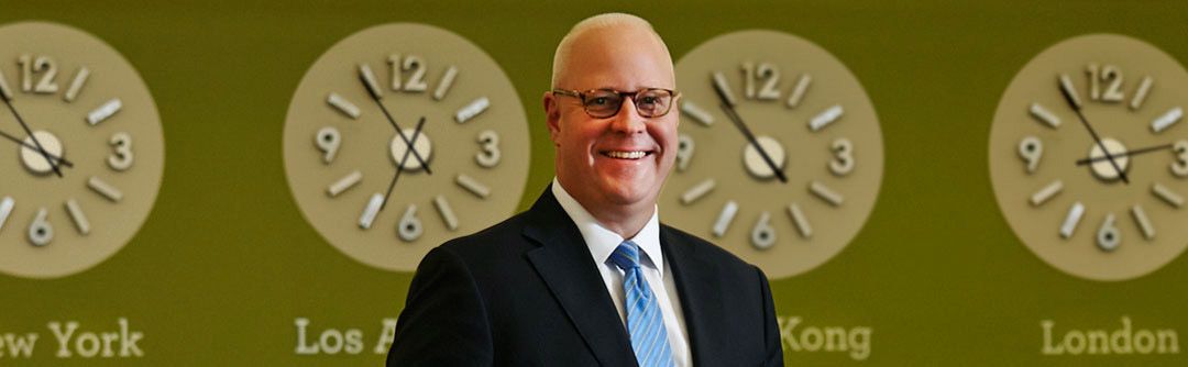 Darrell Cronk in front of clock for different time zones