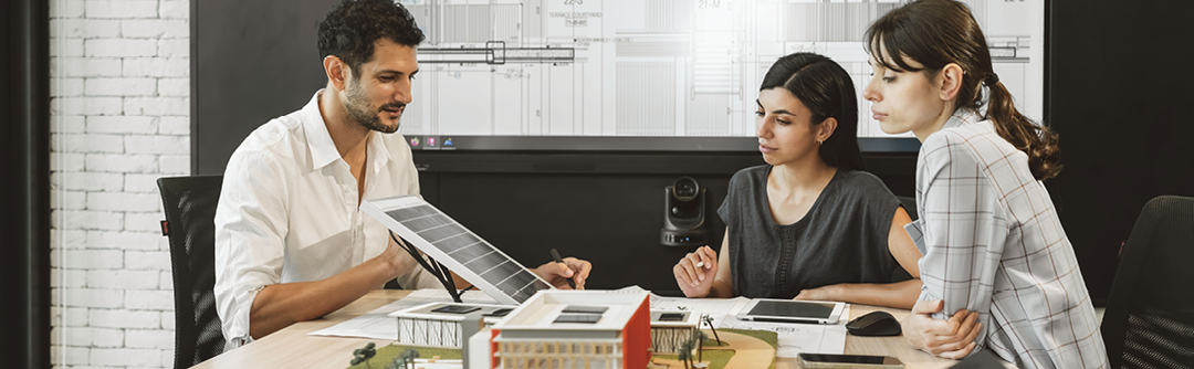 A group of people in a conference room sitting at a table looking over documents
