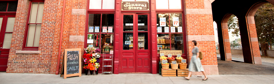 A woman walking by general store front.