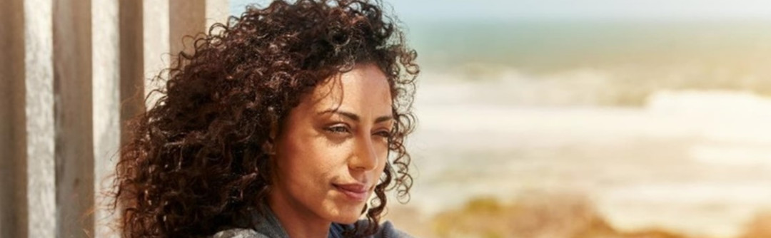 A woman seated on patio overlooking the beach.