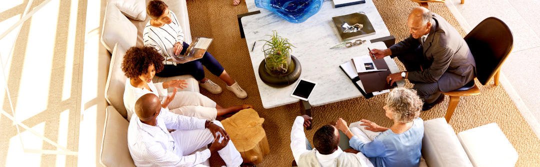 A multigenerational family seated in the living room talking.