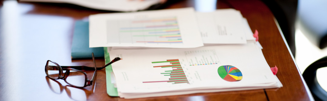 Financial documents with a pair of glasses placed on a desk.