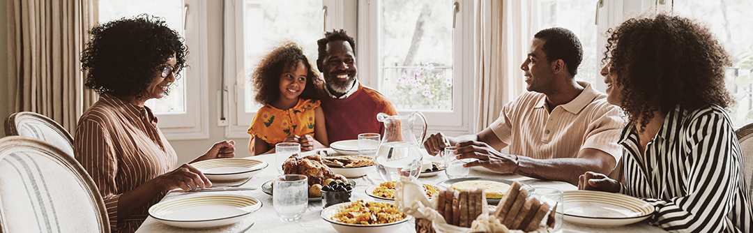 Multigenerational family seated at dinner table.