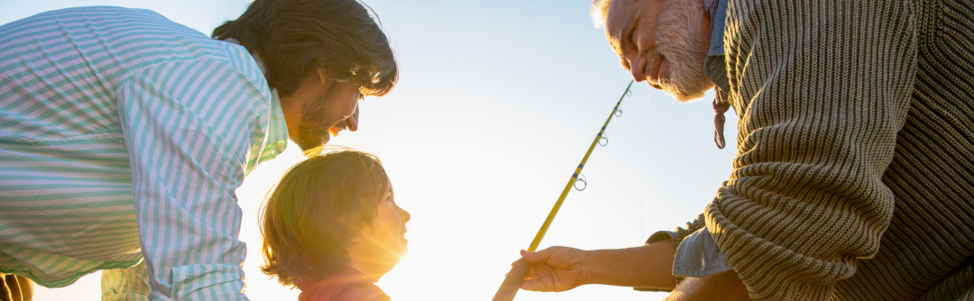 Grandfather and father teaching grandson how to fish.