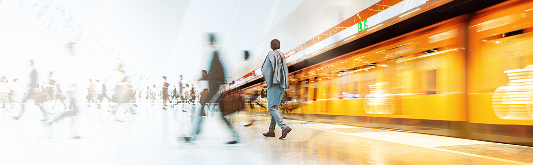 Image of man in focus in train station surrounded by blurred images of other travellers