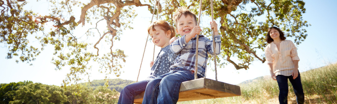Mother pushing kids on a swing