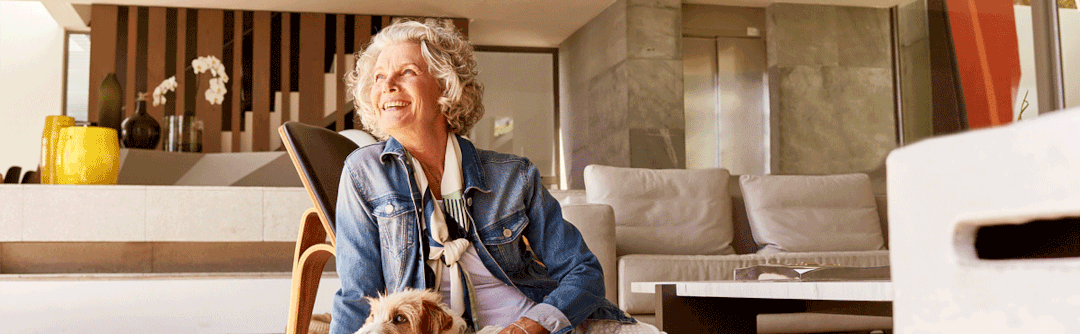 Woman seated on living room floor with her dog.