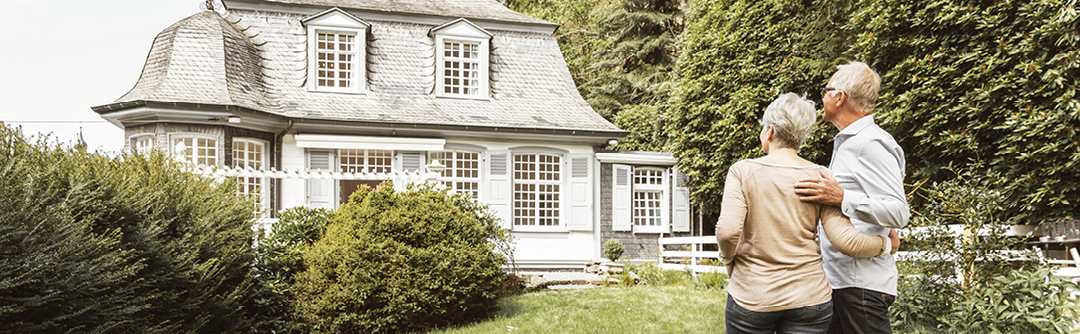 Two people holding each other while looking at a house