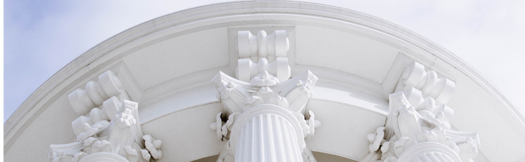 Upward view of ornate concrete columns holding up a building