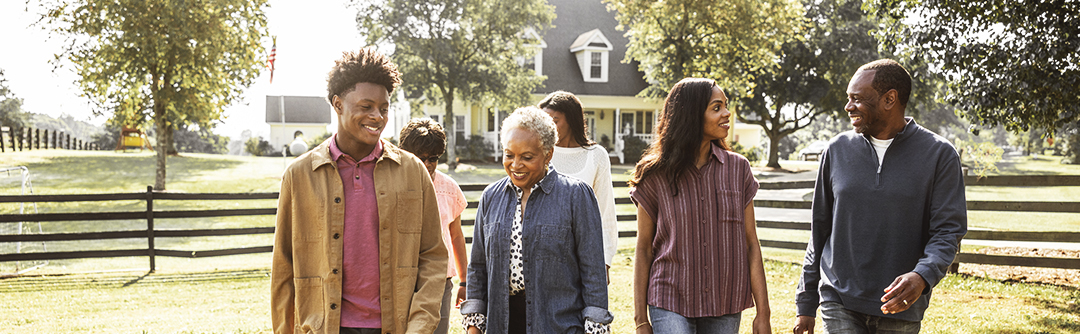 Group of adults walking along fenced countryside near a house.
