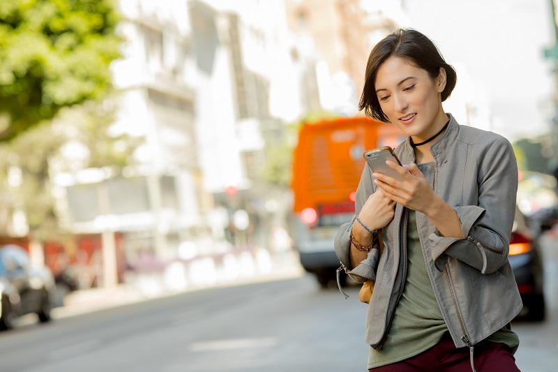 A woman looking at her phone on a city street