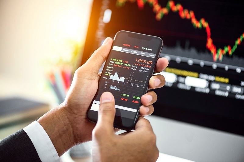 close up of a man holding a cell phone showing stock information