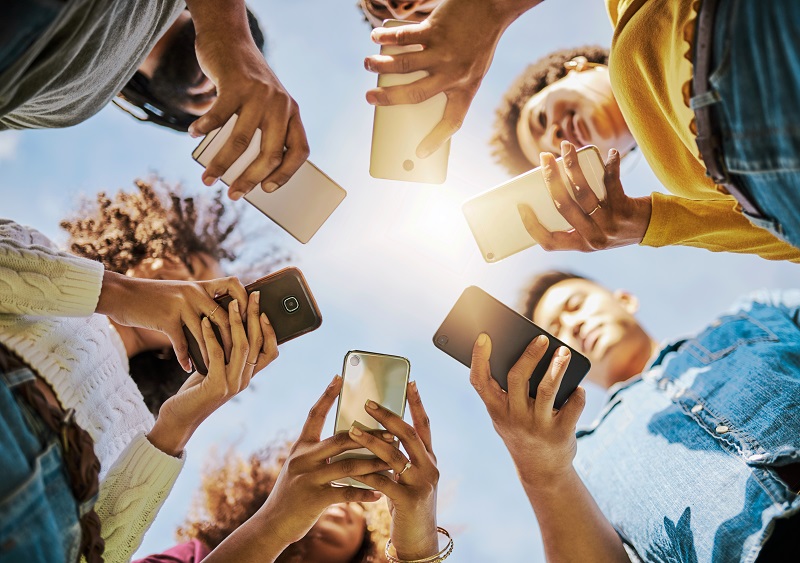 upward view of six people holding their phones in a circle