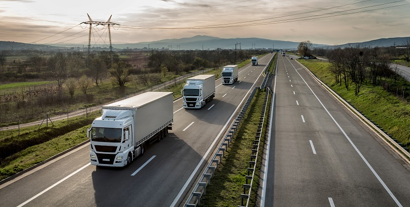 four trucks in a row driving down the highway