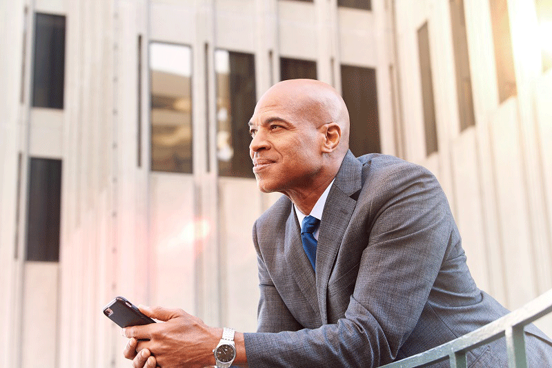 Man with cellphone in hand overlooking balcony of office building