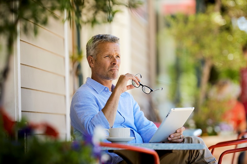 man at patio table with digital tablet