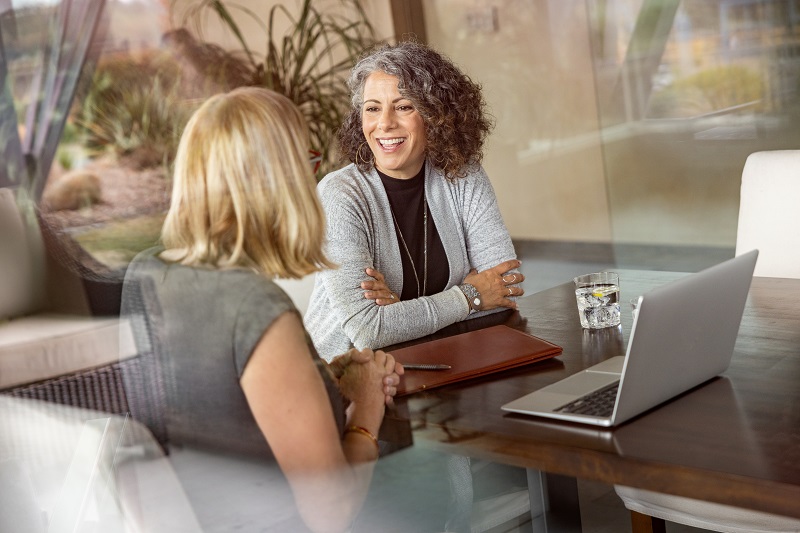 Woman talking to advisor with a laptop on table.