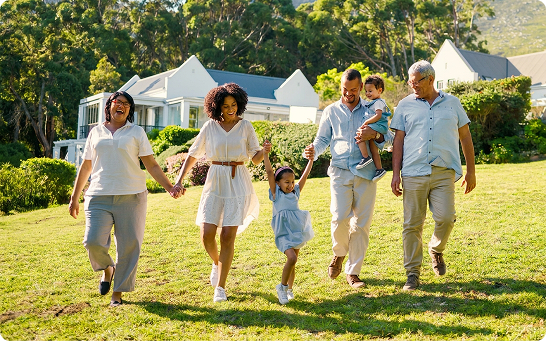 Five people, including two children, walking together across a grassy yard near several houses.