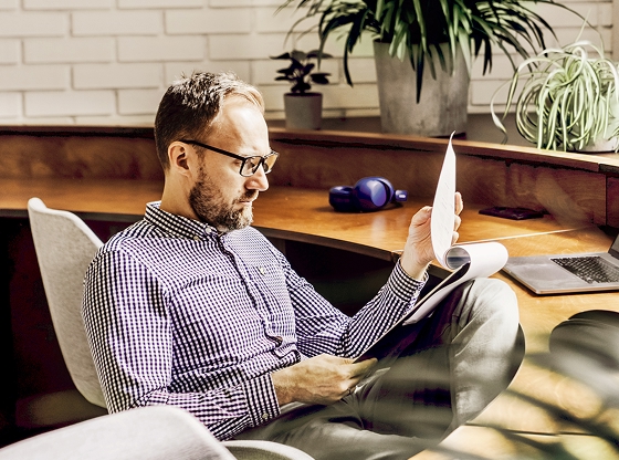 Man seated at office desk reviewing paperwork.