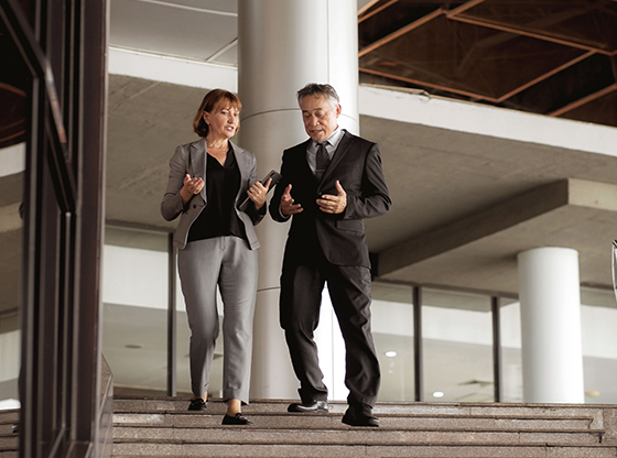 Two businesspeople talk as they walk down a staircase – Wells Fargo