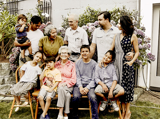 A multigenerational family gathered outdoors, showing adults and children interacting warmly.
