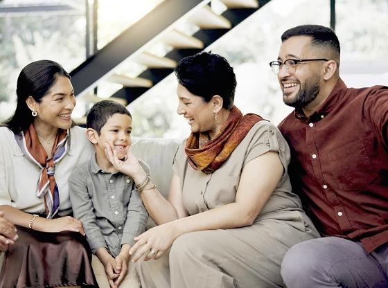 A multi-generational family sitting together indoors, engaged in a conversation.