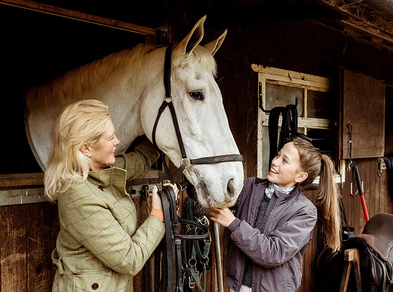 Mother and daughter greet a horse at the stables.