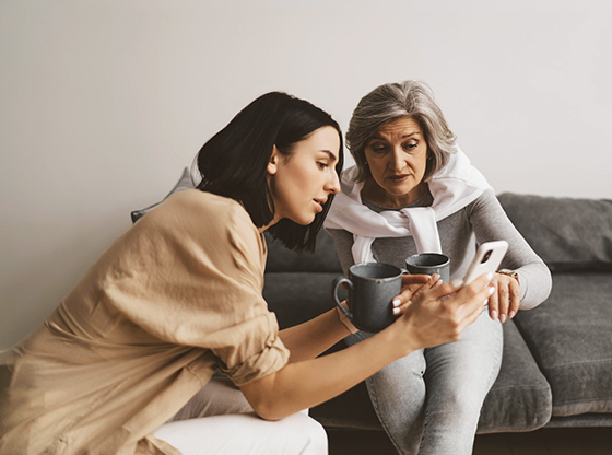 A mother and daughter viewing a smartphone in their living room.