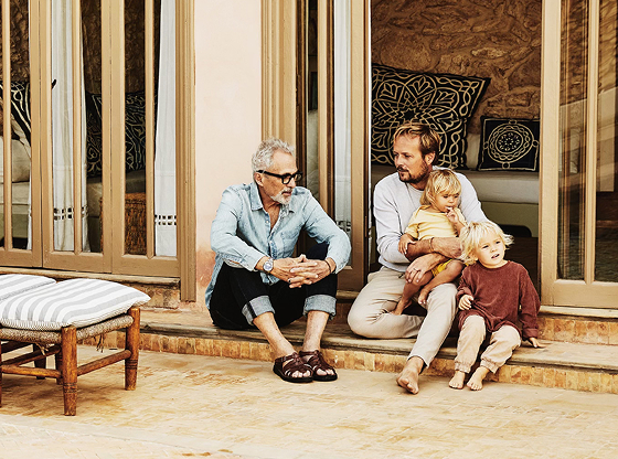 Grandfather, adult son, and two young grandchildren seated on backyard patio.