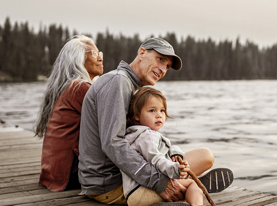 A couple sitting by a lake with a child.