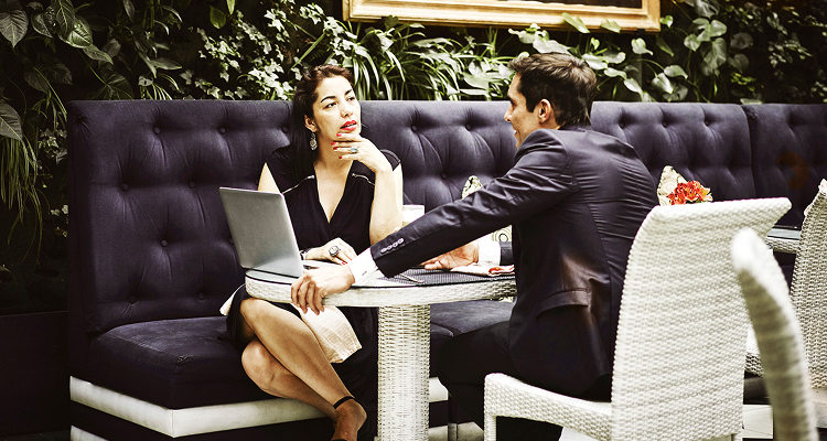 Two people sitting at a table, engaged in conversation with a laptop open in front of them.