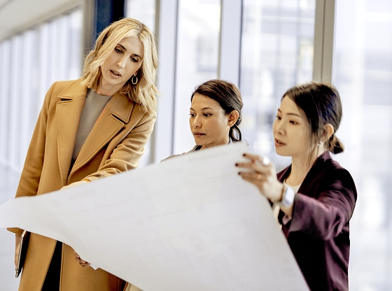 Three businesswomen review a document while in the office.