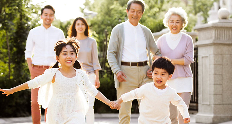Multigenerational family walking outdoors in a sunny setting.