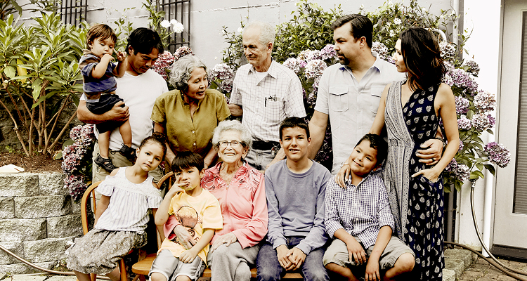 A multigenerational family gathered outdoors, showing adults and children interacting warmly.