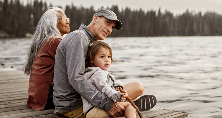 A couple sitting by a lake with a child