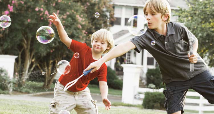 Two children playing with bubbles in a yard