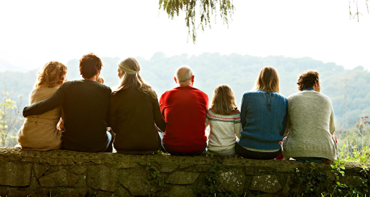 Multigenerational family sitting on a stone wall outside
