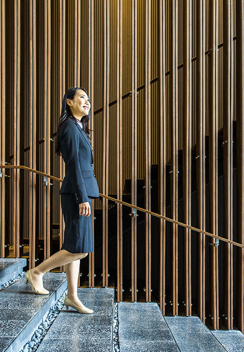 Business professional walking up a staircase in a modern building with vertical wooden architectural panels