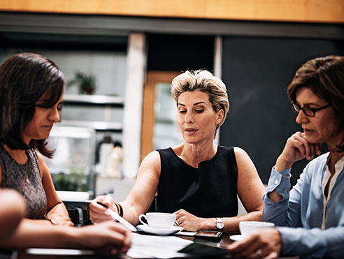 Business professionals seated around a table reviewing documents in a modern office setting