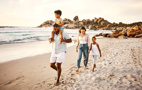 Family walking on the beach at sunset.