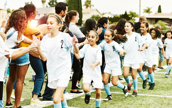 Girls soccer team high-five their parents.